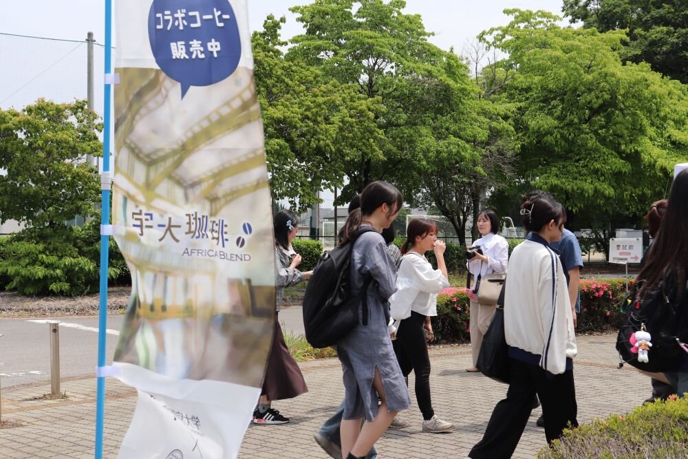 宇大珈琲の旗とコーヒーを試飲する学生たち