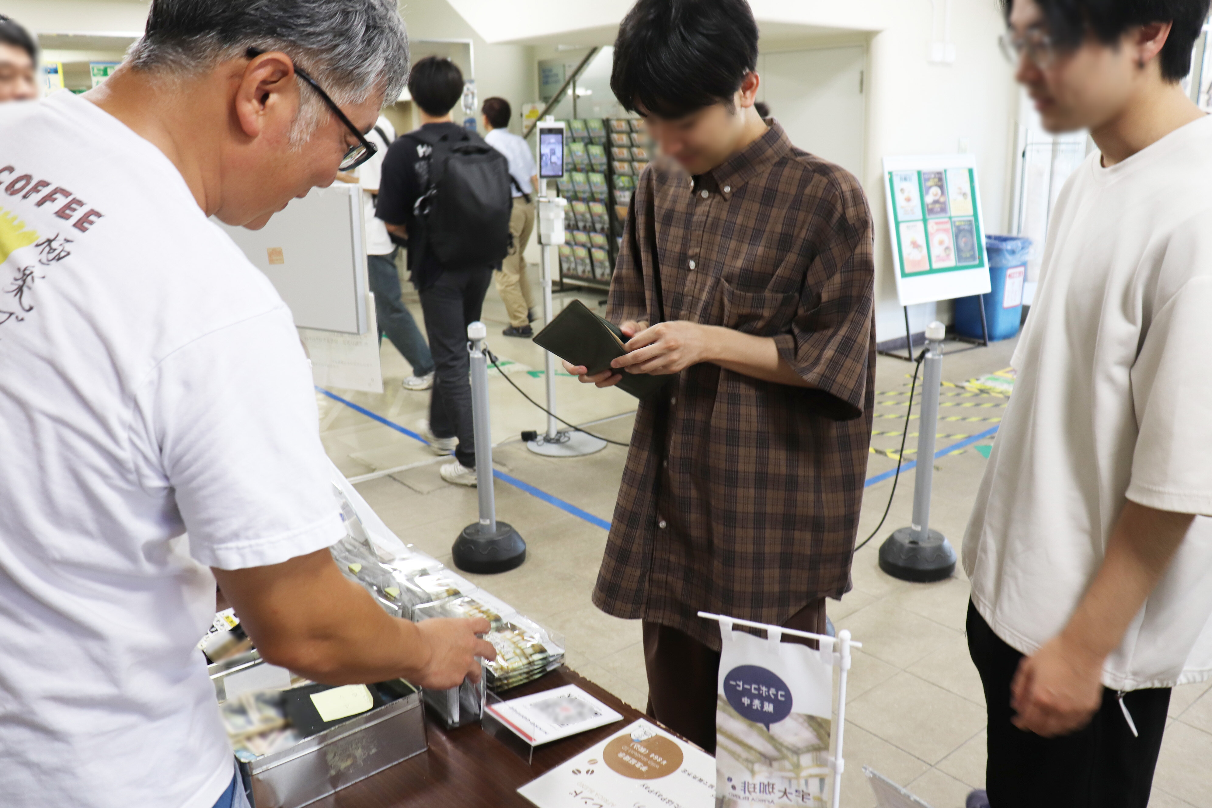 宇大珈琲の旗とコーヒーを試飲する学生たち