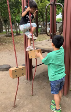 職員の子供2人が公園の遊具で遊んでいる写真