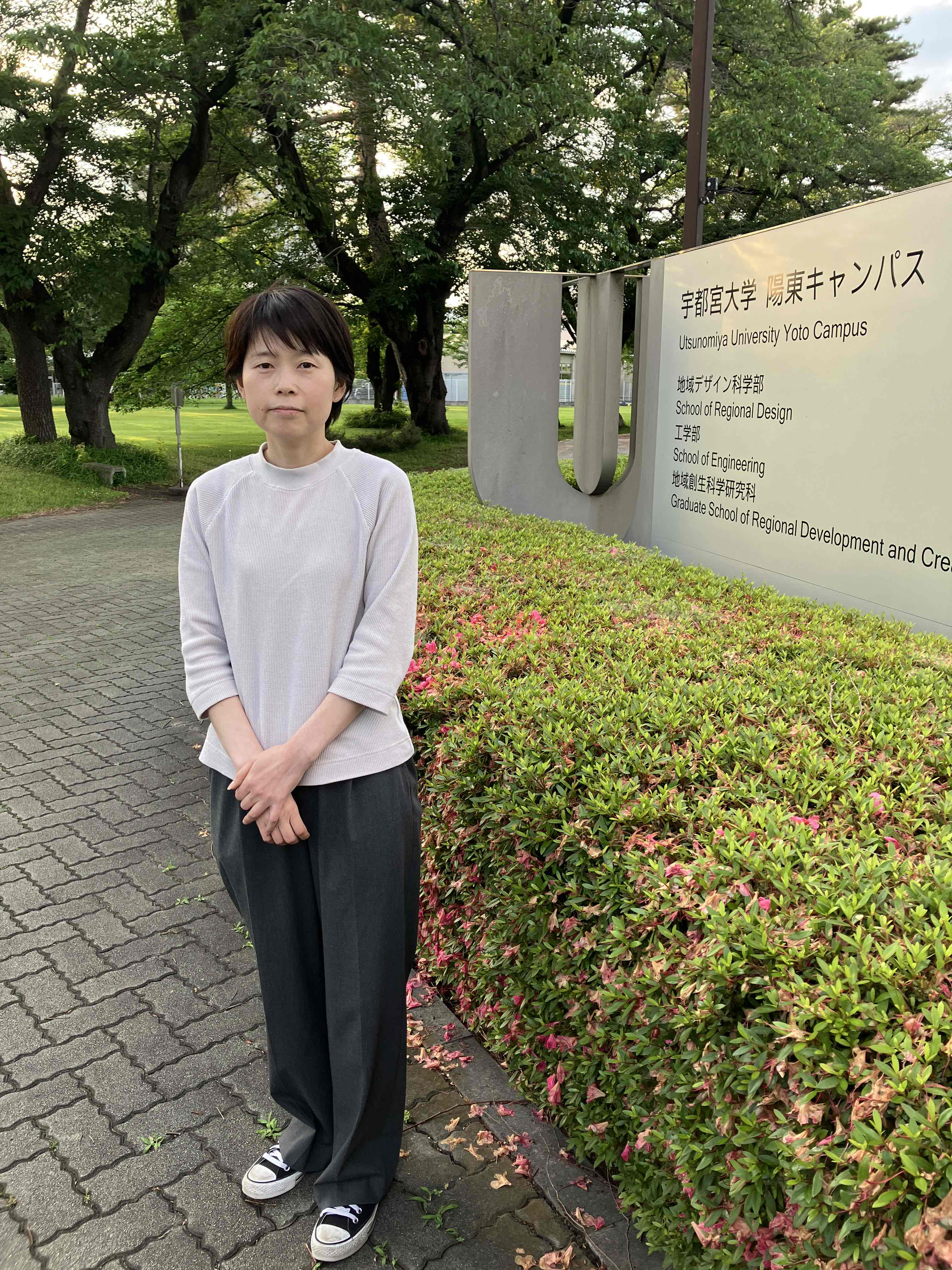 陽東キャンパスの看板前で撮影した職員の写真