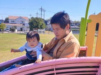 職員が子供1人とすべり台で遊んでいる写真