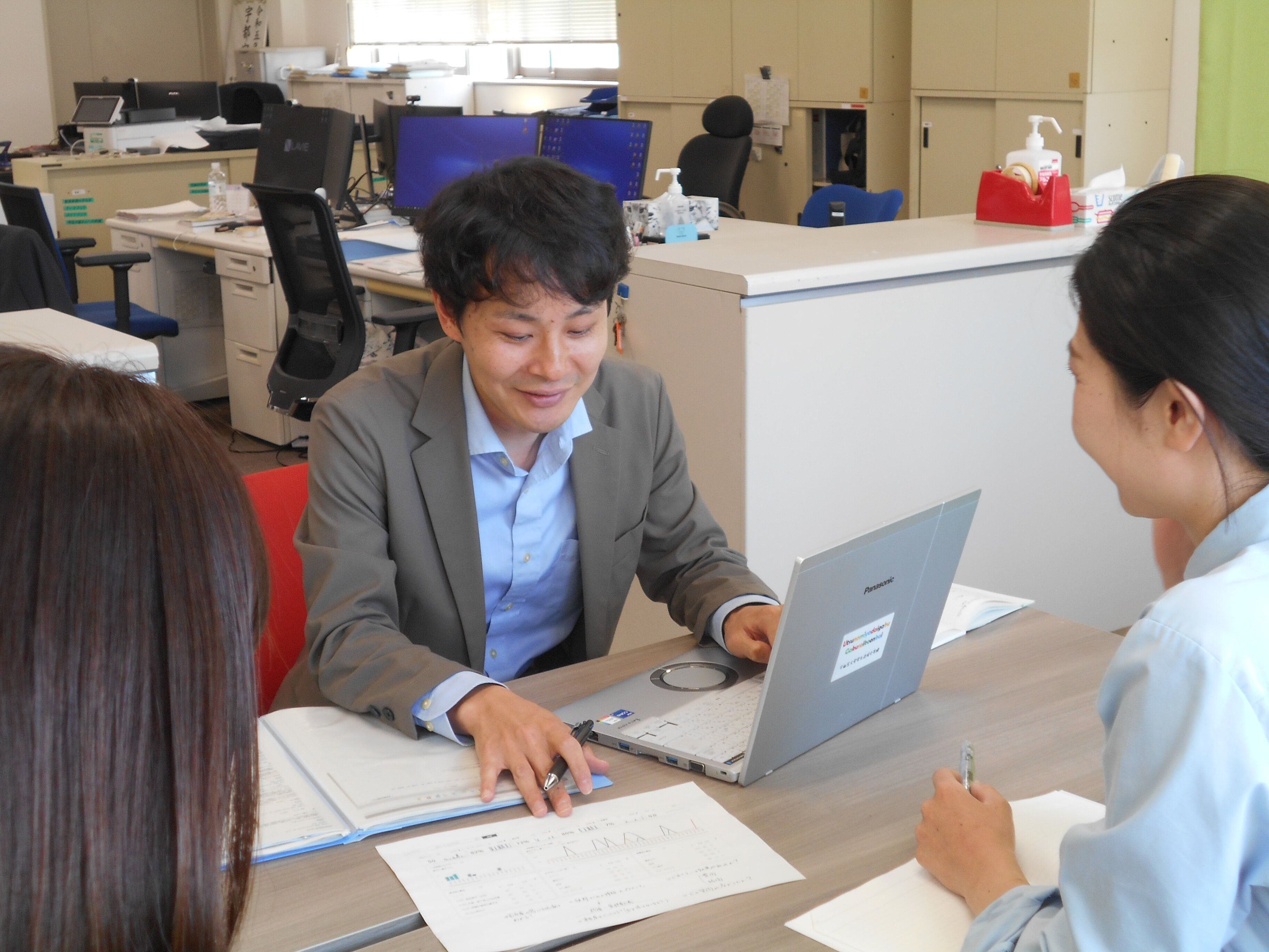 職員がパソコンを操作しながら打ち合わせをしている写真