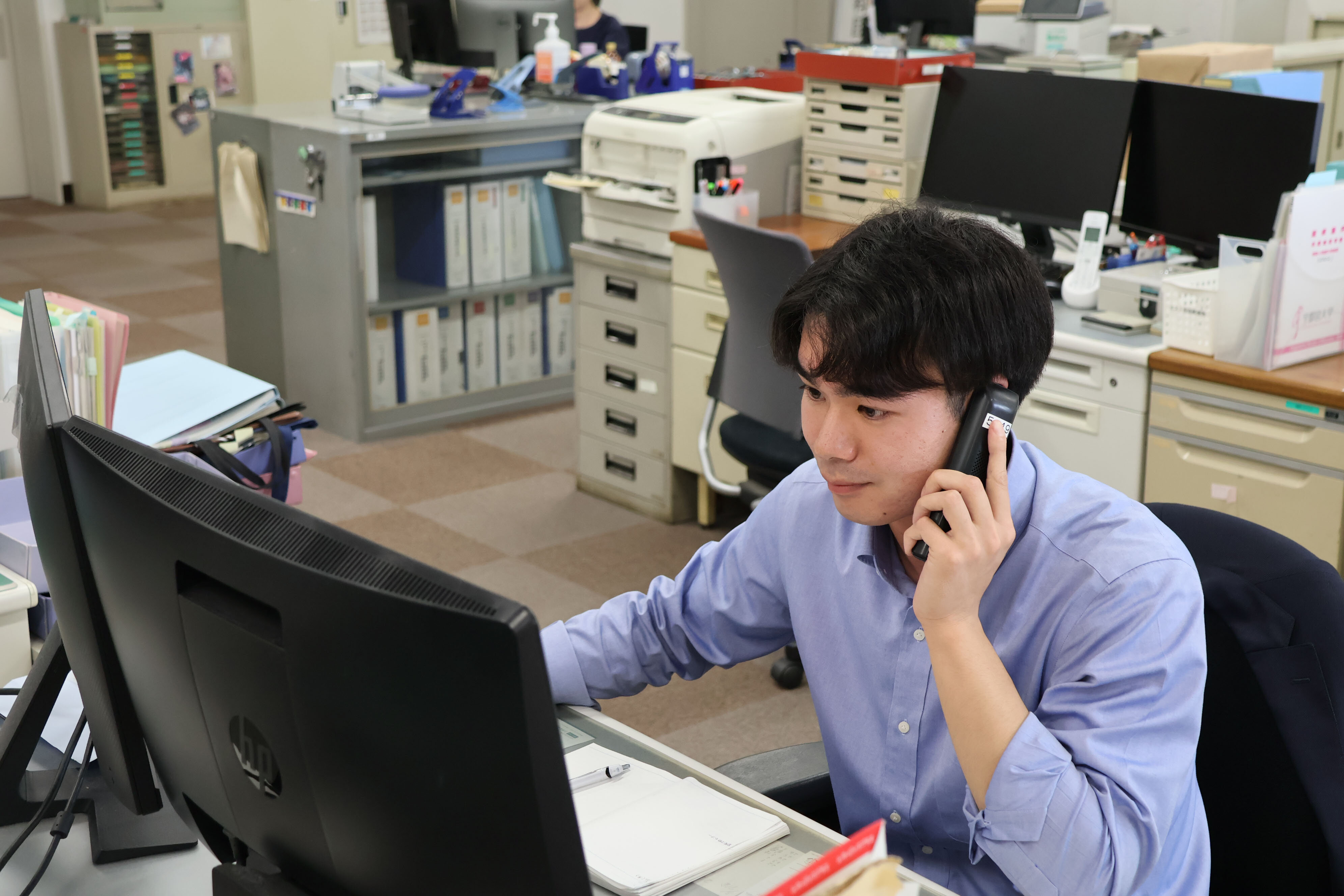職員が電話しながらパソコンを操作している写真