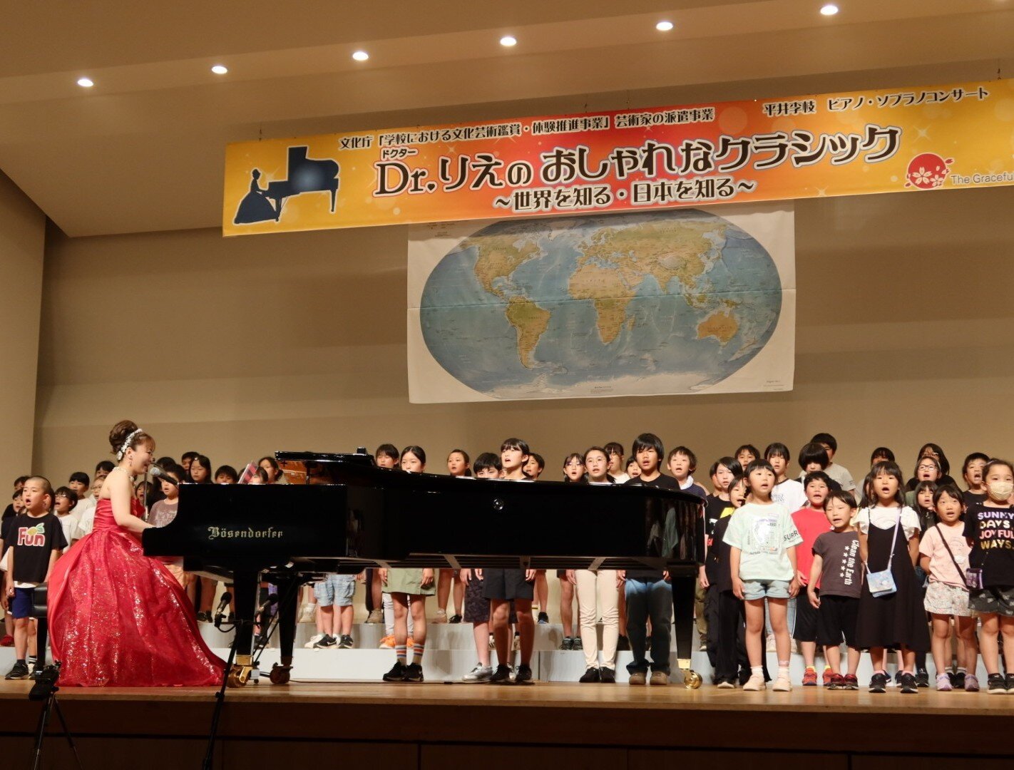 大勢の子どもたちとステージで演奏する平井先生